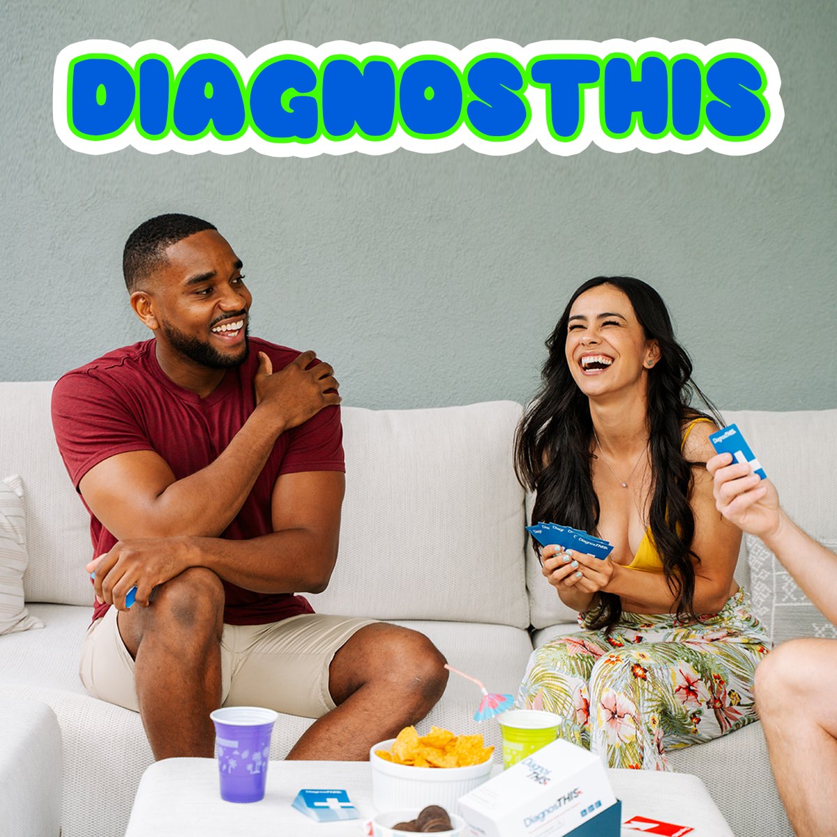 A pair on a sofa playing a Thrilly card game with drinks in hand